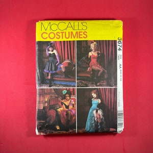 May include: A vintage McCall's Costumes sewing pattern. The yellow and white package features four images of women in elaborate costumes. The costumes include a black dress with a top hat, a red dress, a black dress with a teal hat, and a blue dress.