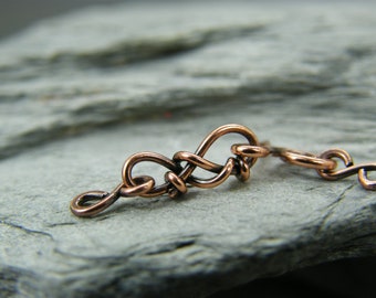 May include: A close-up of a copper wire chain link, showing the intricate detail of the woven design.