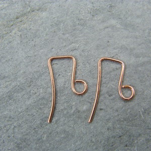 May include: Two rose gold earring hooks. The hooks are made of wire and have a simple, elegant design.