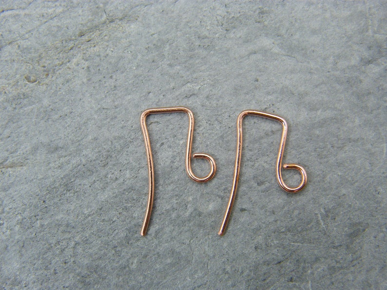 May include: Two rose gold earring hooks. The hooks are made of wire and have a simple, elegant design.