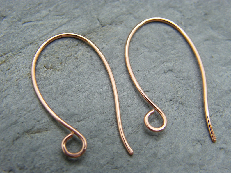 May include: Two rose gold earring hooks. The hooks are made of thin wire and have a small loop at the end.