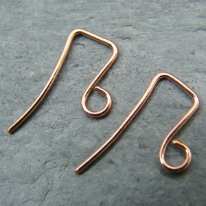 May include: Two rose gold earring hooks. The hooks are made of wire and have a simple, elegant design.