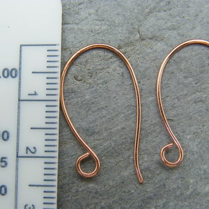 May include: Two copper earring hooks, each measuring approximately 2.5 inches in length. The hooks are made of a thin, flexible wire and have a small loop at the end.
