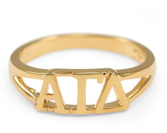May include: A gold ring with the letters "AIA" cut out of the band.