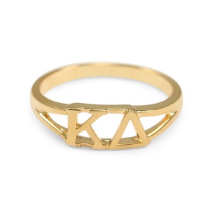 May include: A gold ring with the letters "KA" in a cut-out design.
