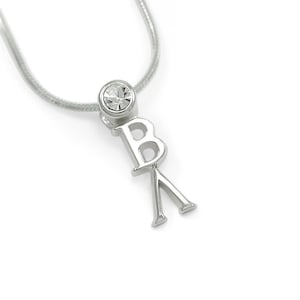 Könnte beinhalten: Silberkette mit einem Kristall-Anhänger und einem Anhänger mit den Buchstaben "BK".