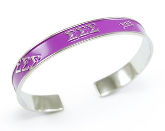 May include: A silver bangle bracelet with a purple enamel band and the letters "ΣΣΣ" engraved on it.