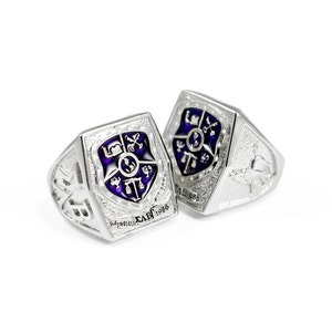 May include: Two silver rings featuring a purple enamel crest with a shield and various symbols. The rings are engraved with the text "ΣΑΒΓ 1986".