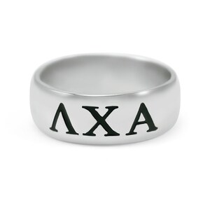 Puede incluir: Un anillo de plata con las letras "AXA" grabadas en negro.
