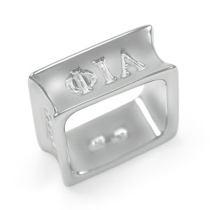 Könnte beinhalten: Silberring mit quadratischer Form und den eingravierten Buchstaben "ΦΙΑ" auf der Oberseite.