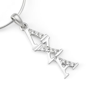 Puede incluir: Un collar con colgante de plata con las letras griegas 'ΑΧΑ'. El colgante tiene un diseño estilizado, con cada letra engastada con pequeñas piedras claras y brillantes. El collar tiene una delicada cadena de plata, sobre un fondo blanco.