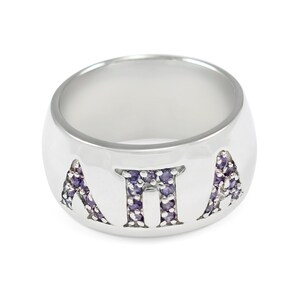 May include: A silver ring featuring the letters "ATA" set with purple gemstones.