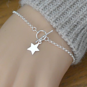 May include: A silver chain bracelet with a star charm and a toggle clasp.