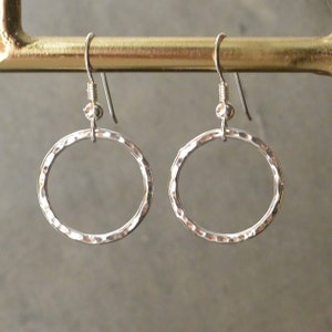 May include: A pair of silver hammered hoop earrings with a simple wire hook fastening.