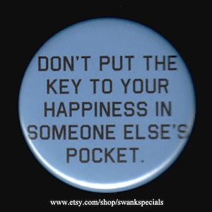 May include: A blue button with the text "DON'T PUT THE KEY TO YOUR HAPPINESS IN SOMEONE ELSE'S POCKET." The text is in black and the button has a white border.