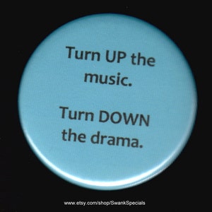 Może przedstawiać: Okrągły, jasnoniebieski guzik z tekstem "Turn UP the music. Turn DOWN the drama." Tekst jest czarny. Guzik ma białą obwódkę.
