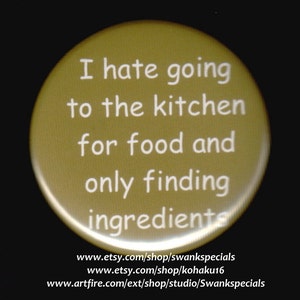 May include: A gold round button with white text that reads "I hate going to the kitchen for food and only finding ingredients". The button also includes the website addresses "www.etsy.com/shop/swankspecials", "www.etsy.com/shop/kohaku16", and "www.artfire.com/ext/shop/studio/Swankspecials".