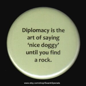 Diplomacy is the art of saying 'nice doggy' until you find a rock.   Pinback button or magnet.