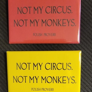 May include: Two yellow and red rectangular magnets with the text "NOT MY CIRCUS. NOT MY MONKEYS. POLISH PROVERB" printed in black.