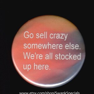 May include: A round button with a red, orange, and yellow gradient background. The text on the button reads: "Go sell crazy somewhere else. We're all stocked up here."