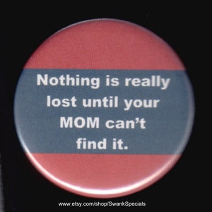 Puede incluir: Un botón redondo rojo y azul con el texto "Nothing is really lost until your MOM can't find it." El botón es redondo y tiene un borde blanco.