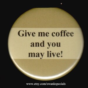 May include: A gold button with the text "Give me coffee and you may live!" printed in black. The button is a round shape with a white stripe across the middle.