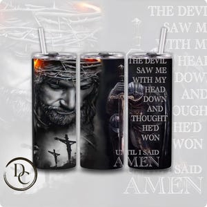 May include: A black and white tumbler with a graphic of Jesus Christ wearing a crown of thorns. The text "The Devil Saw Me With My Head Down And Thought He'd Won Until I Said Amen" is printed on the tumbler.