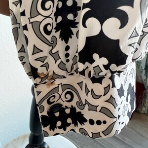May include: Black and white patterned fabric with a grey and black paisley design. The fabric has a white background with black and grey swirls and shapes.