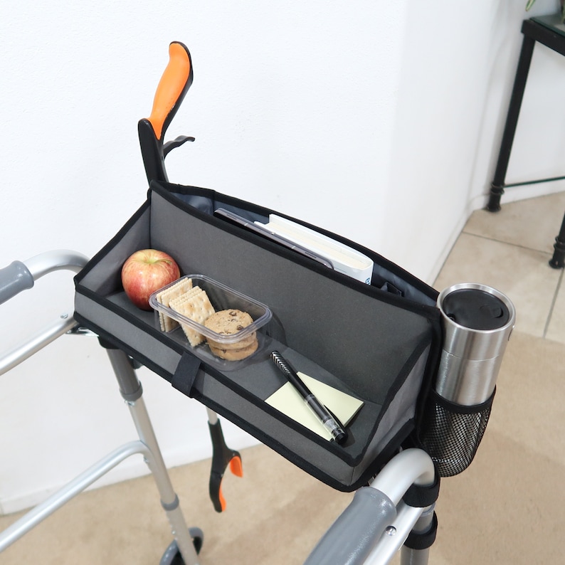 The tray on this walker basket is designed to be able to fold-up and out of the way when not in use, and back down when in use. A small velcro strap holds the tray on this walker bag in the closed position. This walker caddy offers much convenience.