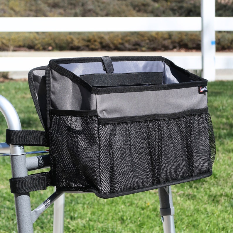 Walker basket with small flip-down tray to place small items conveniently in front of you, such as glasses, phone, small snacks, etc. Also has a small strap to hold a cane or umbrella conveniently with the walker bag, and 5 pockets, 1 is a cup holder