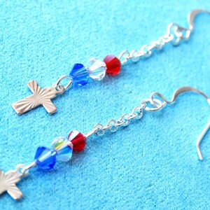 May include: Silver cross earrings with blue and red crystal beads.