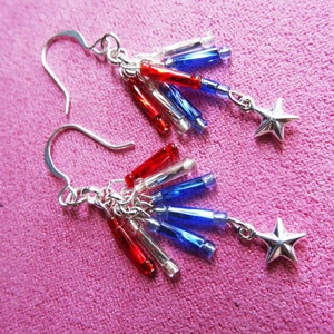 May include: Silver earrings with red, white, and blue beads and star charms. The beads are arranged in a cascading pattern.