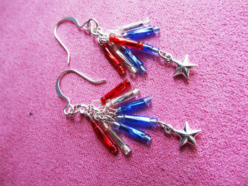 May include: Silver earrings with red, white, and blue beads and star charms. The beads are arranged in a cascading pattern.