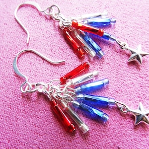 May include: Silver earrings with red, white, and blue star-shaped charms. The charms are made of glass beads and are arranged in a cascading pattern.
