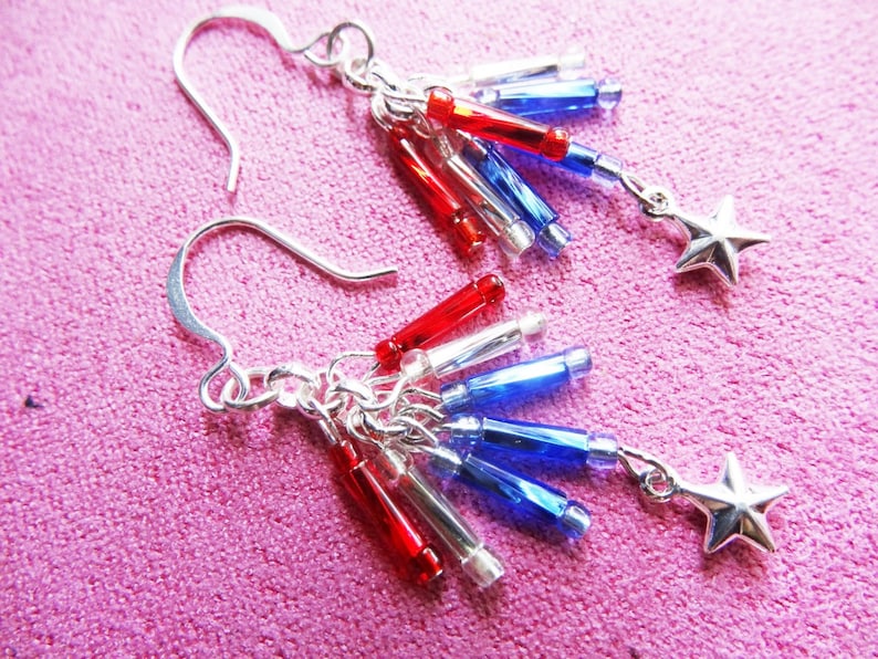 May include: Silver earrings with red, white, and blue star-shaped charms. The charms are made of glass beads and are arranged in a cascading pattern.