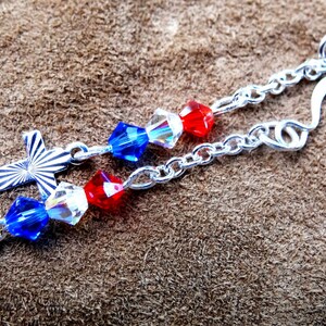 May include: Silver earrings with red, white, and blue crystal beads and silver cross charms.