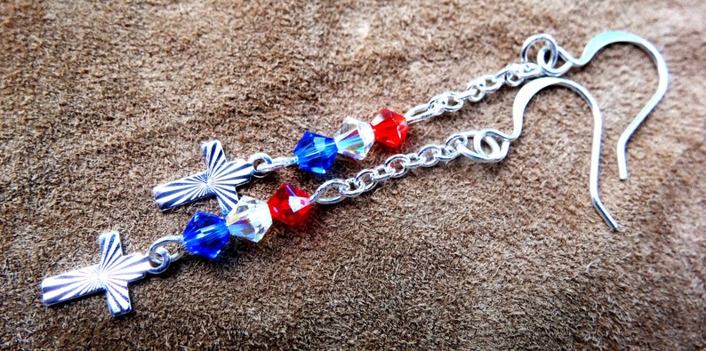 May include: Silver earrings with red, white, and blue crystal beads and silver cross charms.