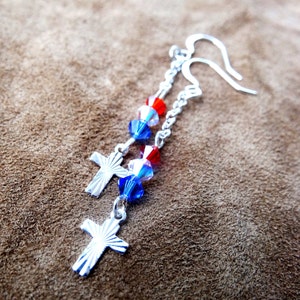 May include: Silver dangle earrings with red, white, and blue crystal beads and silver cross charms.