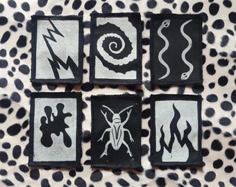 Parches de algodón negro con grabado en linóleo, serpientes estampadas a mano con bloques, inserciones y parches de llamas.