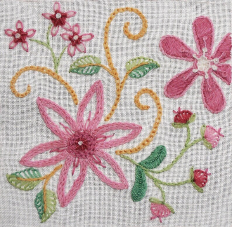 May include: Embroidered floral design on a white linen fabric. The design features pink flowers with yellow stems and green leaves.