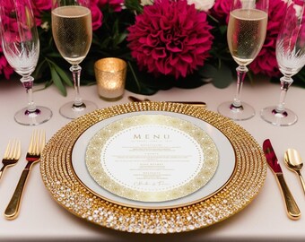 May include: A gold charger plate with a white plate and a gold and white menu card on top. The menu card says "MENU" at the top and has a gold glitter design. The table is set with gold flatware and champagne flutes.