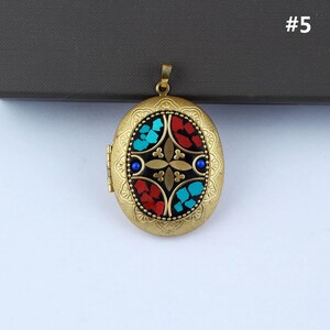 May include: Gold oval locket with a black background and a colorful mosaic design. The mosaic features red, blue, and turquoise pieces arranged in a geometric pattern.