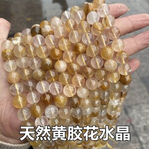 K&ouml;nnte beinhalten: Eine Kette aus goldenen Rutilquarz-Perlen. Die Perlen sind rund und durchscheinend, mit goldenen Einschl&uuml;ssen, die wie schimmernde F&auml;den aussehen. Die Perlen sind auf einer durchsichtigen Gummikordel aufgef&auml;delt.