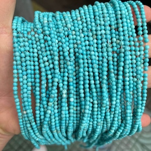 May include: A strand of turquoise beads, approximately 2mm in diameter, strung on a clear thread. The beads are a vibrant blue-green color and have a smooth, polished finish.