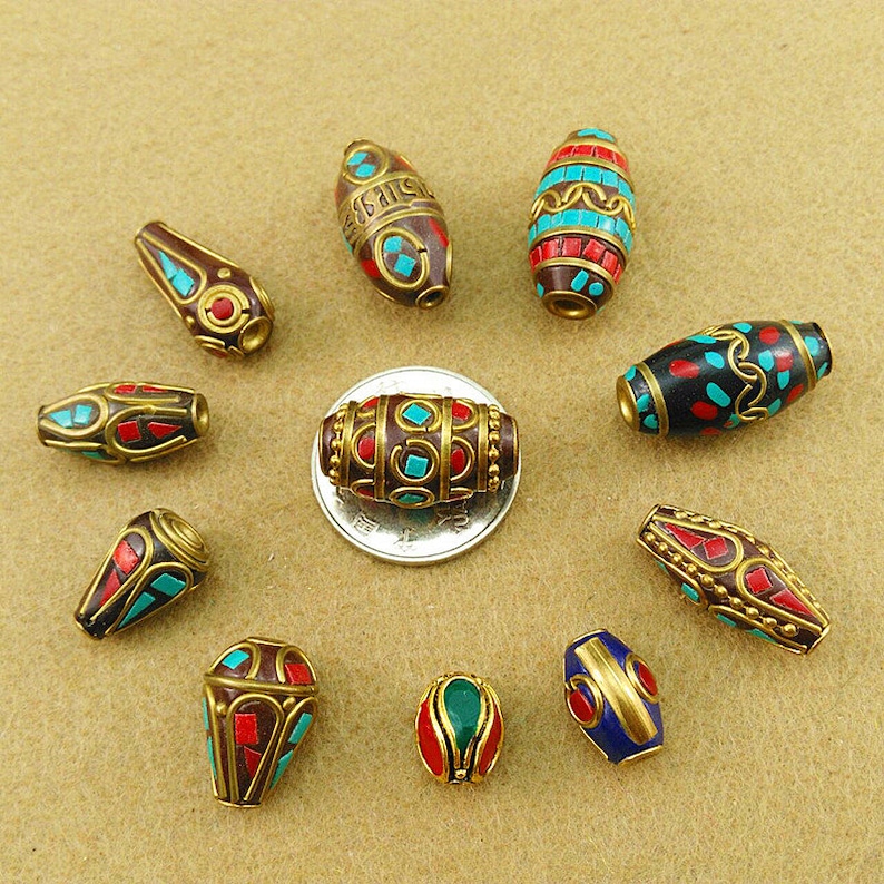 May include: Assortment of 10 Tibetan prayer beads, each with a unique design featuring red, blue, and turquoise enamel and gold accents. The beads are made of brass and are approximately 1 inch in length.