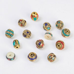 May include: Assortment of round and oval beads with intricate designs and colorful inlays. The beads are made of brass and feature turquoise, red, and blue accents.