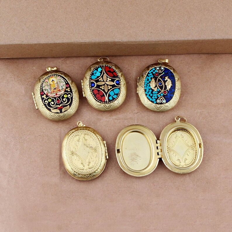 May include: Five oval-shaped gold locket pendants with intricate designs. Two pendants feature colorful mosaic patterns, one has a Buddha image, and two are plain gold.