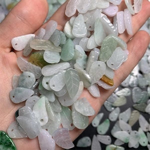 May include: A collection of light green jade leaf-shaped pendants with a hole at the top for stringing. The pendants are carved with delicate leaf veins and have a smooth, polished finish.