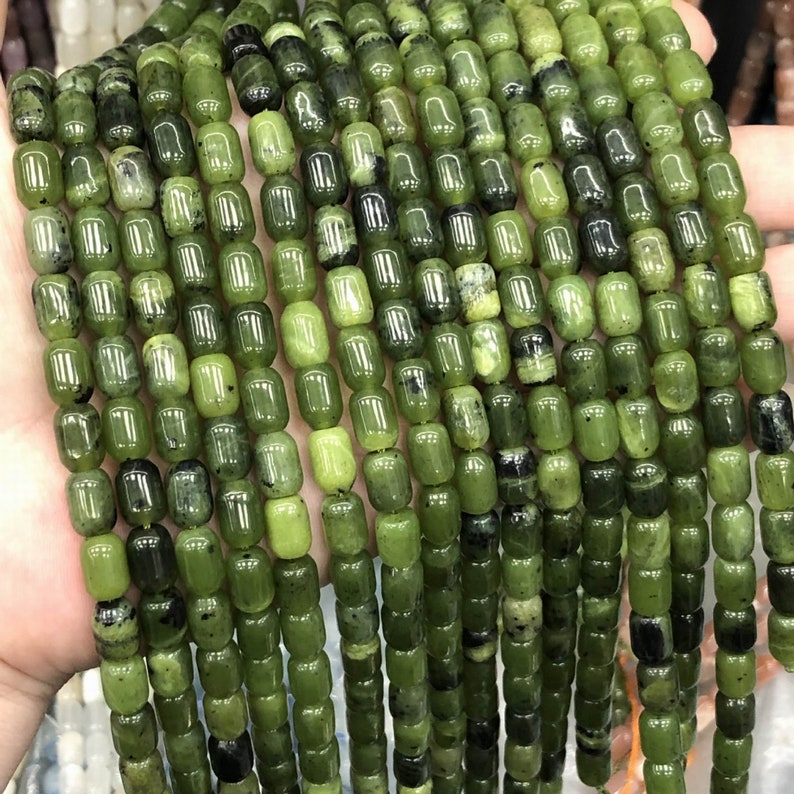 Pode incluir: Um fio de contas de jade verde, cada conta &eacute; um cilindro redondo e liso com uma forma ligeiramente irregular. As contas s&atilde;o enfiadas em um fio transparente.