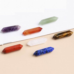 May include: Set of seven double-pointed crystal wands in various colors, including amethyst, carnelian, green aventurine, clear quartz, tiger's eye, red jasper, and lapis lazuli.